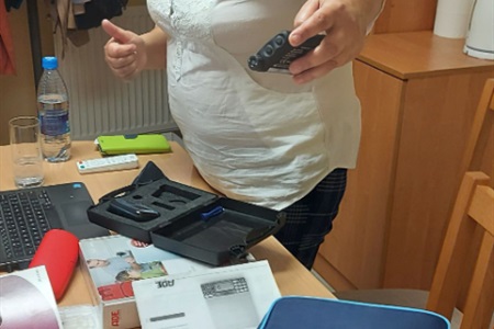 kobieta trzyma w dłoni urządzenie o nazwie pompa insulinowa, na stole leżą materiały szkoleniowe