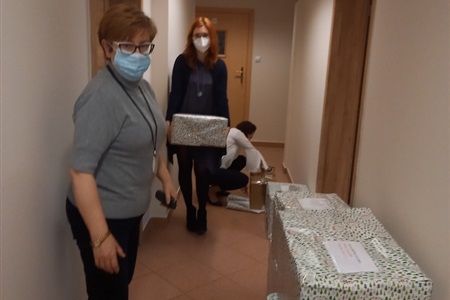 kolorowo zapakowane kartony leżą na korytarzu, obok nich dwie kobiety