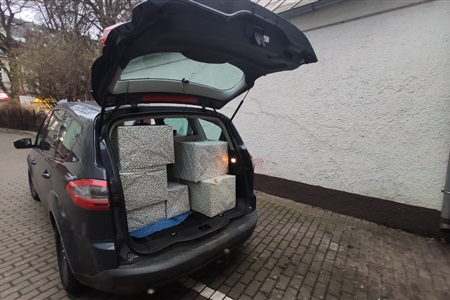kartony zapakowane w kolorowy papier leżą w bagażniku samochodu