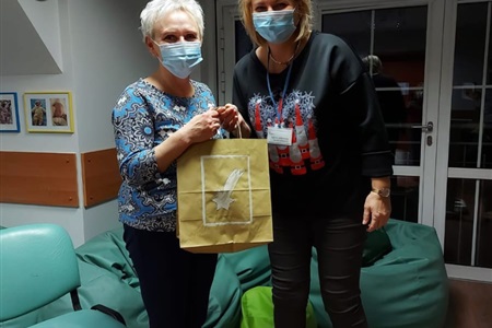 kobieta wręcza papierową torbę prezentową drugiej kobiecie