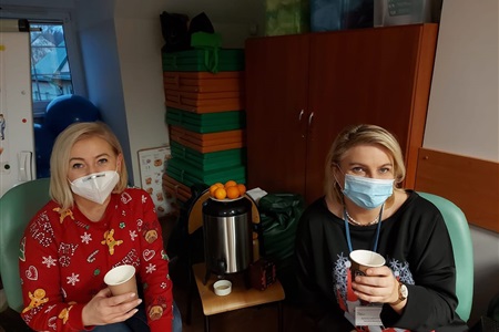 dwie kobiety siedzą, trzymając papierowe kubki