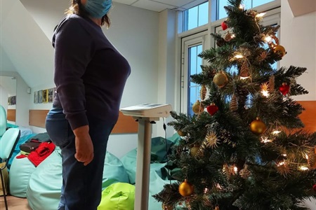 kobieta stoi na wadze, obok stoi choinka