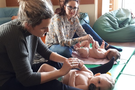 kobiety pochylają się nad leżącymi na plecach dziećmi