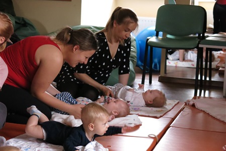 matki nachylone nad dziećmi leżącymi na brzuchu