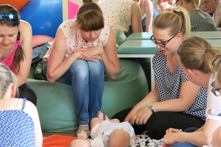 kobiety nachylają się nad leżącym na plecach dzieckiem