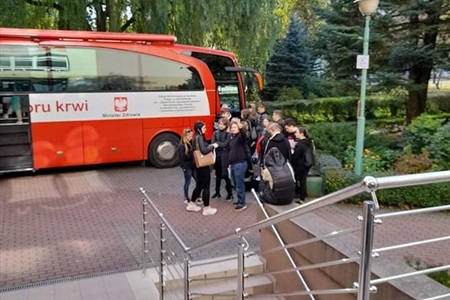 grupa uczniów przed autobusem z godłem Polski